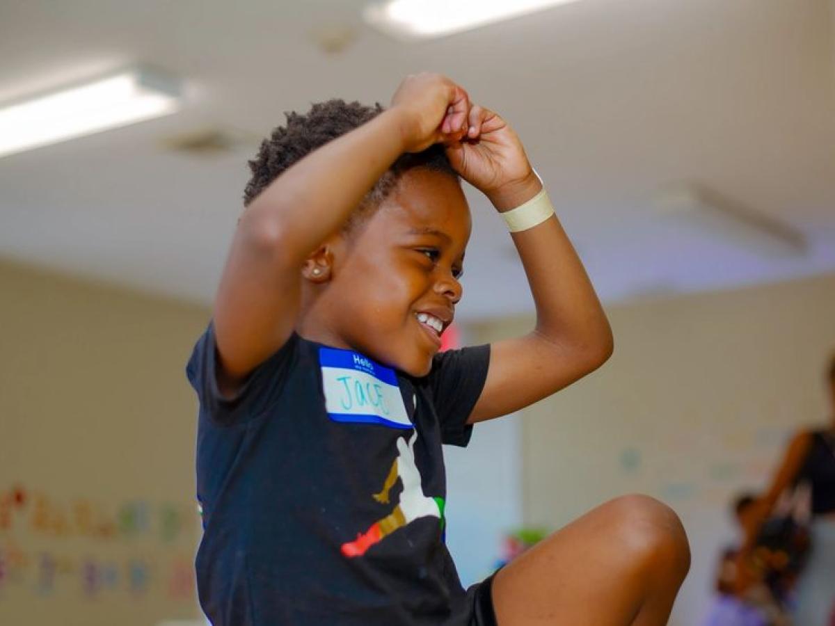 A boy cheering with his arms raised in the classroom